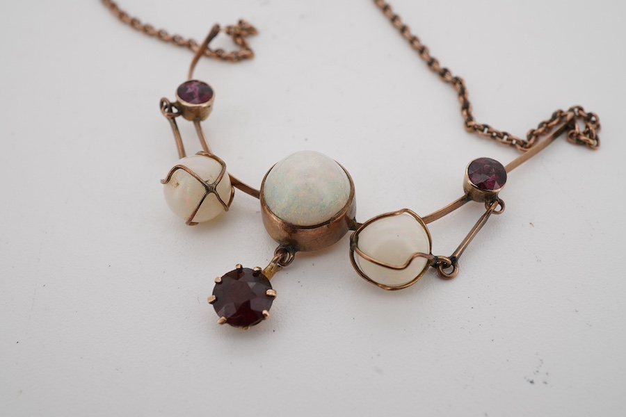 An early 20th century yellow metal, thee stone white opal and three stone garnet set drop necklace, approximately 44cm.